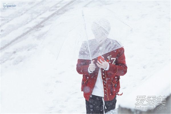 韩璐穿着红色的衣服，手里拿着一把雨伞，在雪地里走着，就像一个王子走出了童话世界。